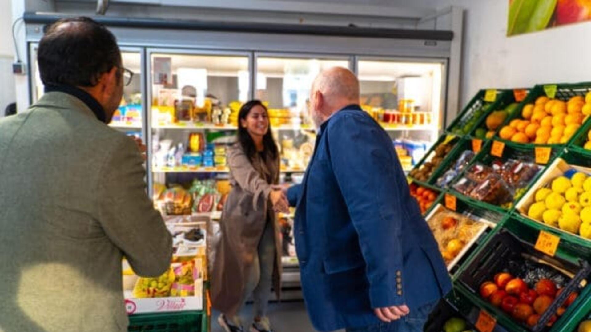 Frans Timmermans schudt de hand van een dame in de supermarkt
